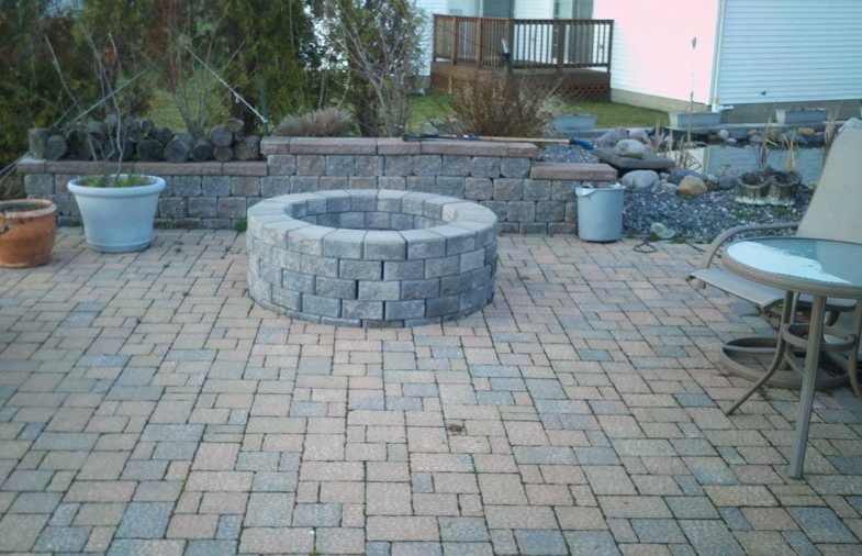 Paver stone firepit on a stone patio in the backyard