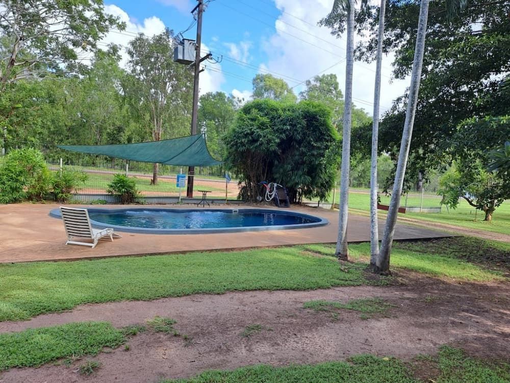 A Large Swimming Pool Surrounded By Trees And Grass in A Park — Cabins in Rum Jungle, NT