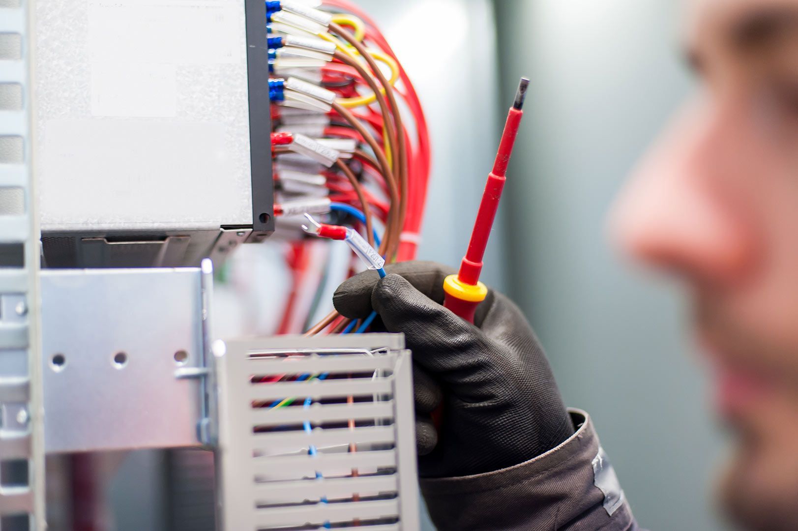 A Man Is Holding A Screwdriver In Front Of A Bunch Of Wires — Wylec In Newcastle, NSW