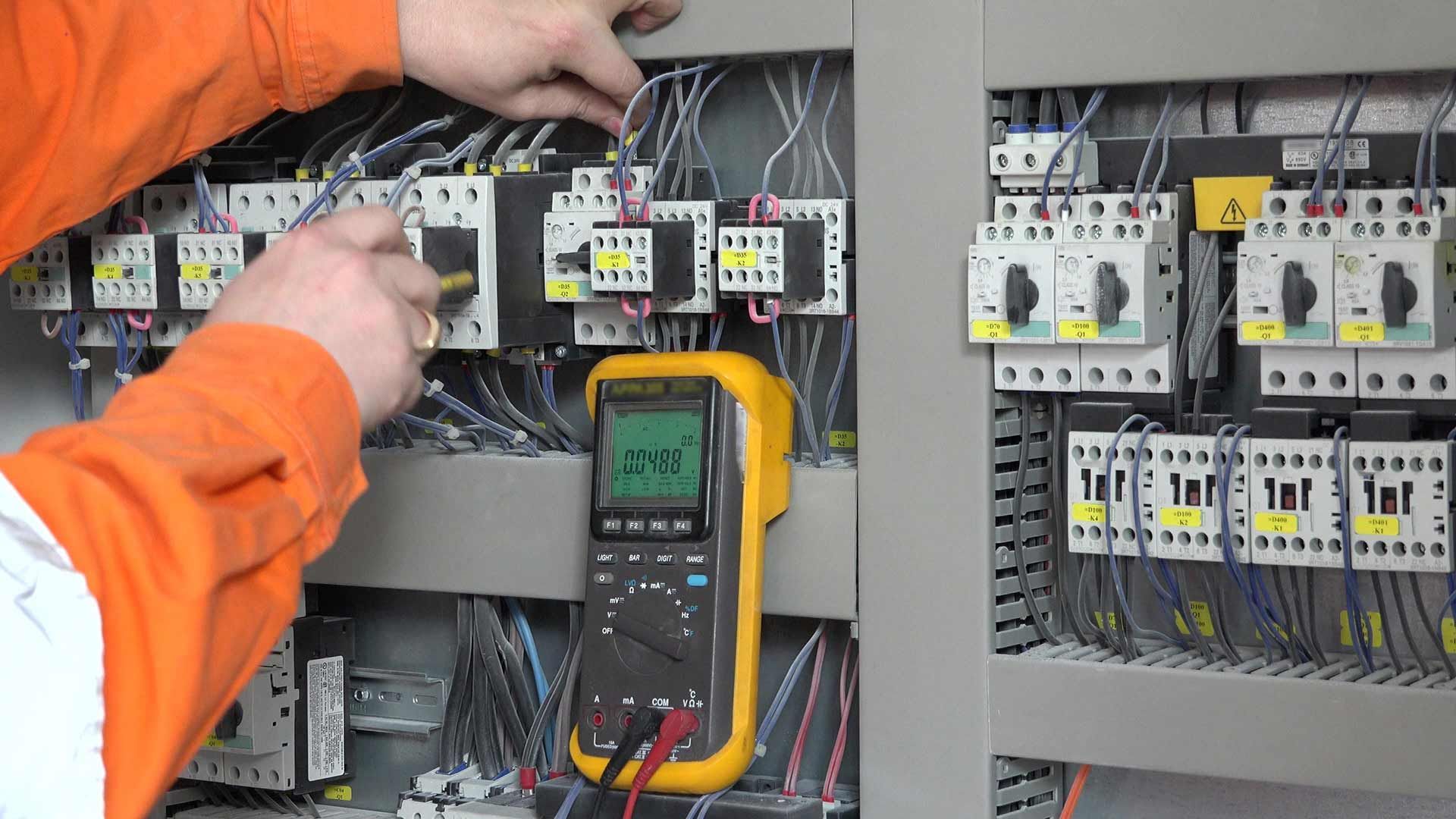 A Man Is Working On An Electrical Panel With A Fluke Multimeter — Wylec In Mayfield West, NSW