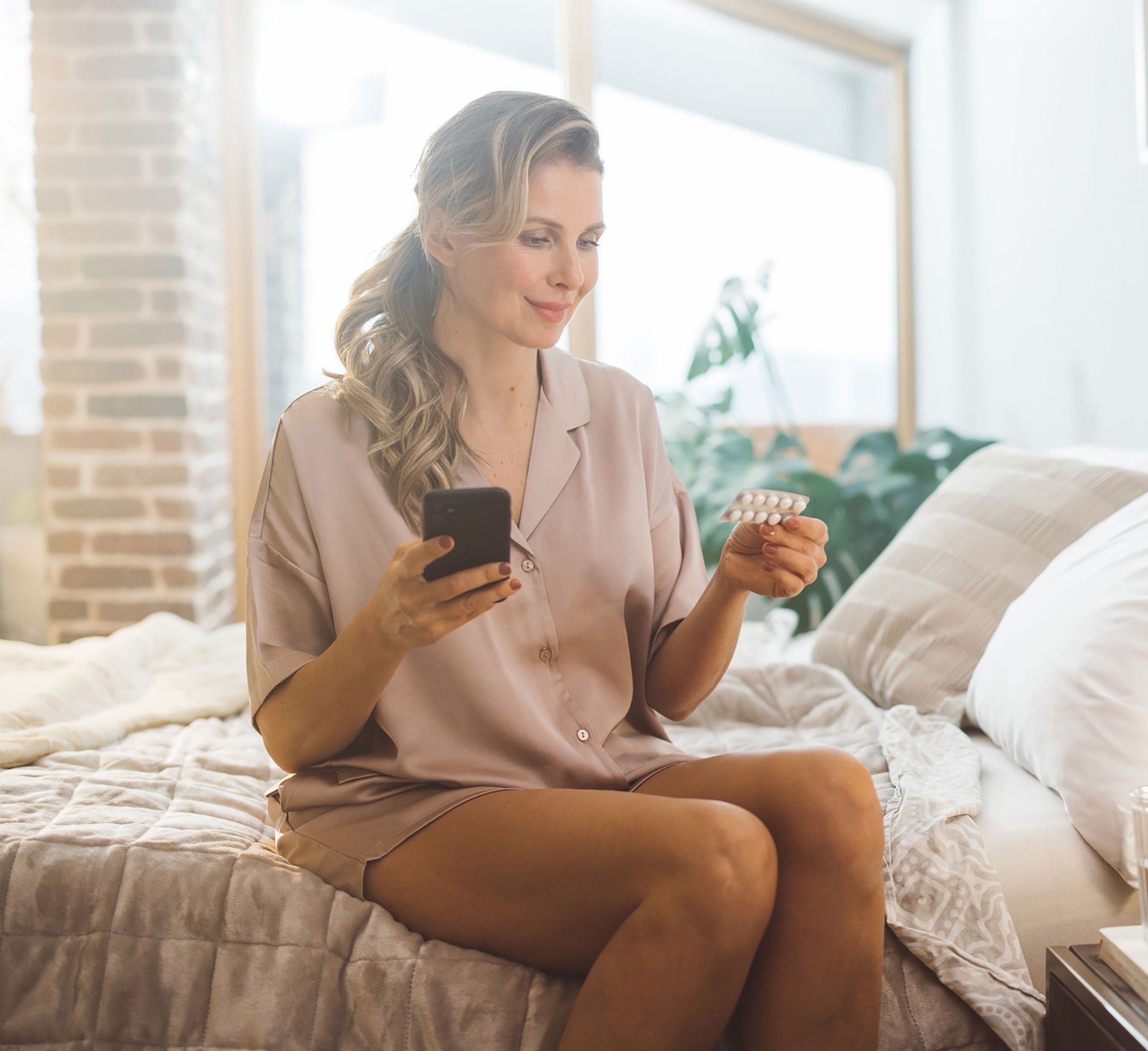 A woman is taking pills on the bed