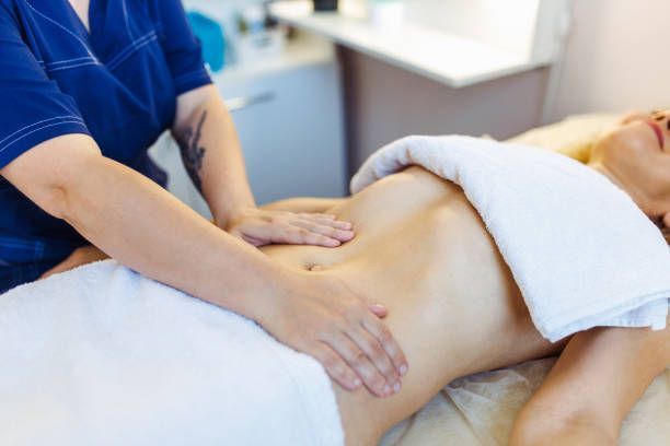 A woman is applying lotion to her shoulder.