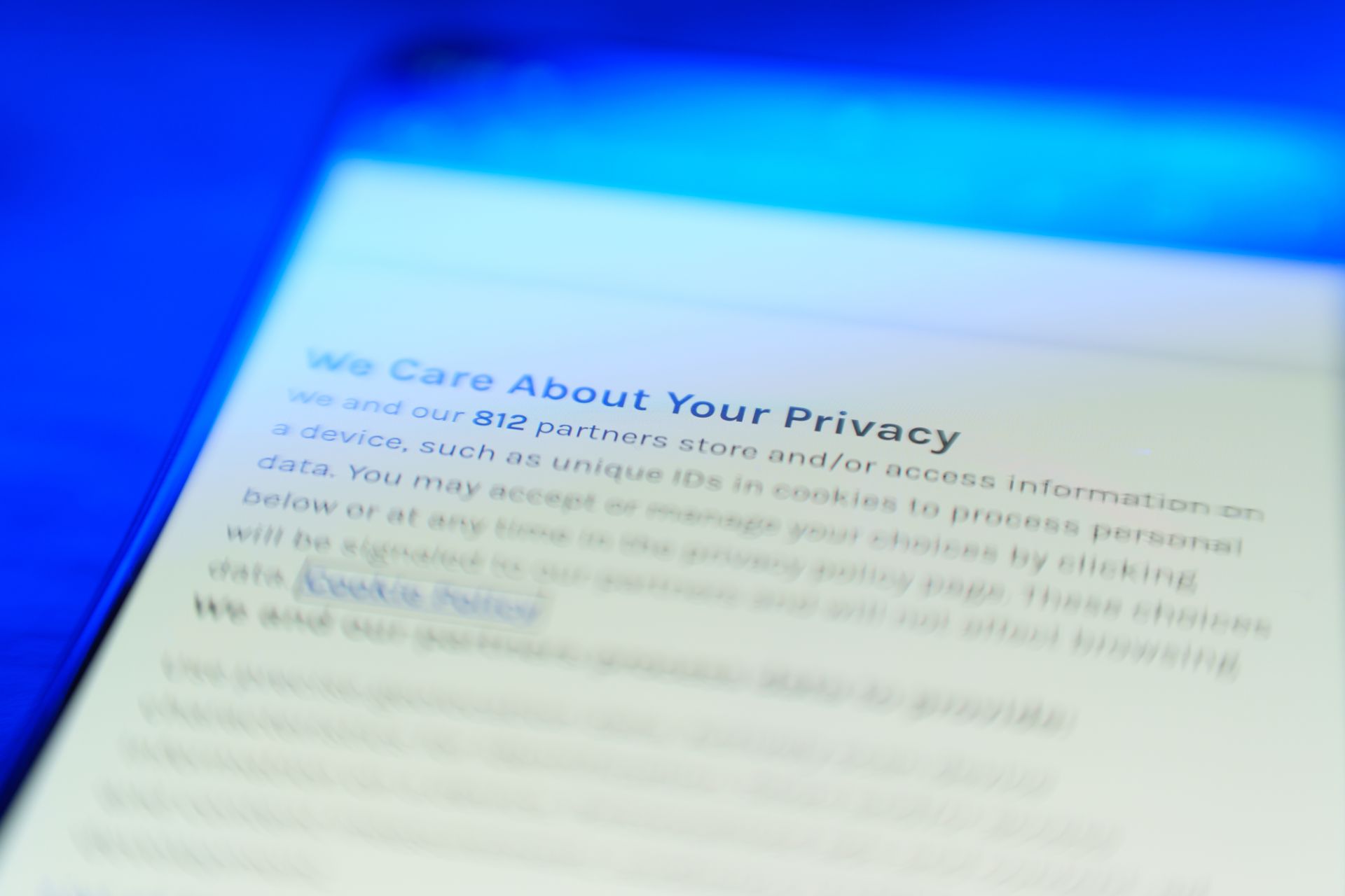 Close-up of a tablet screen displaying a privacy policy statement with blue lighting.