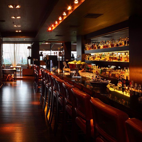 A long bar in a restaurant with lots of bottles on shelves