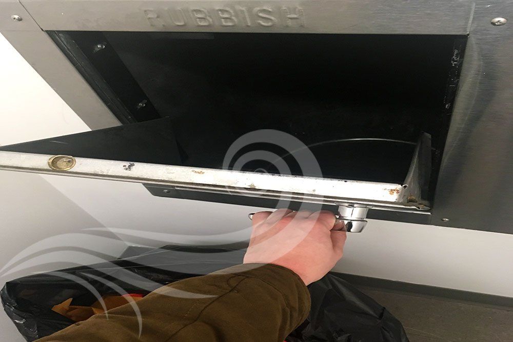 A person is opening a trash can with their hand.