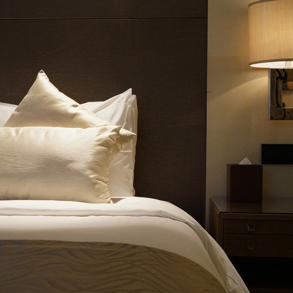 A bed with white sheets and pillows next to a lamp