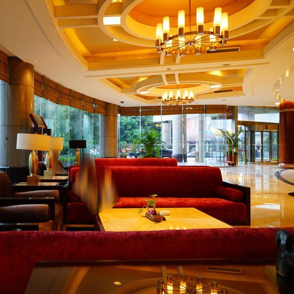 A hotel lobby with red couches and a chandelier