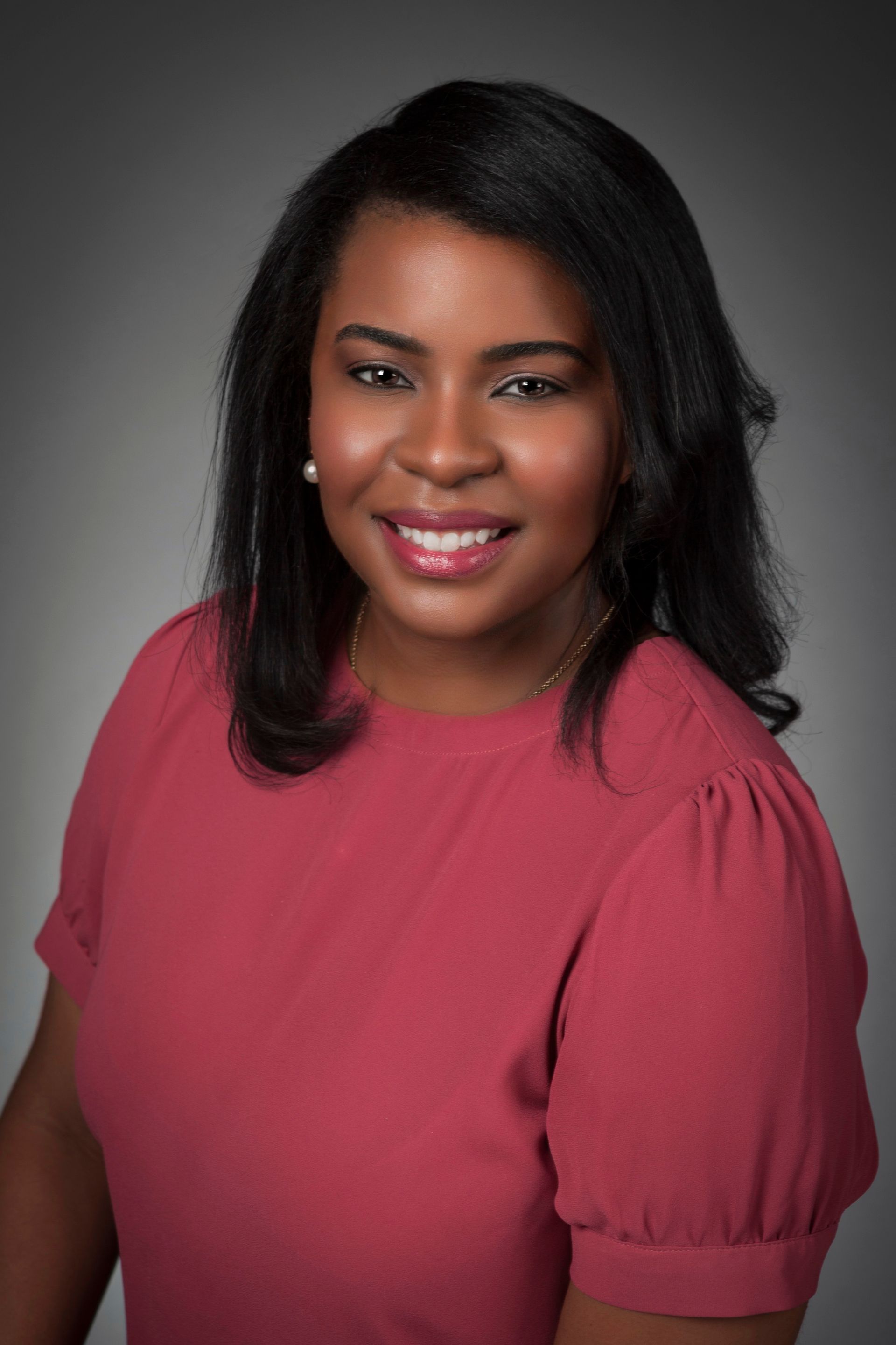 A woman in a red shirt is smiling for the camera.