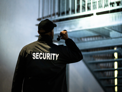 Security guard with flashlight, patrolling stairs in a dim, industrial-looking space.
