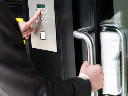 Man in suit entering building, using keypad to unlock door.