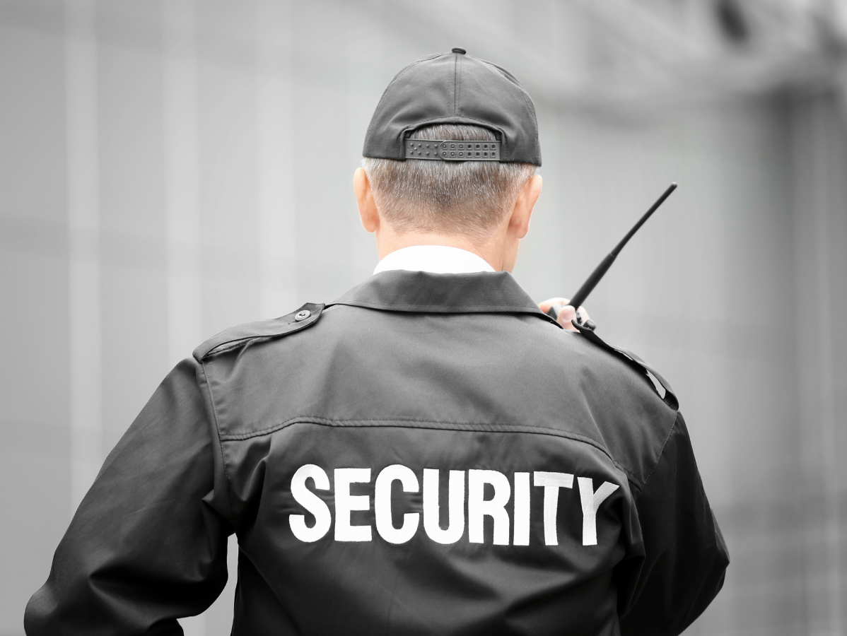 Back view of a security guard in uniform holding a radio, with 