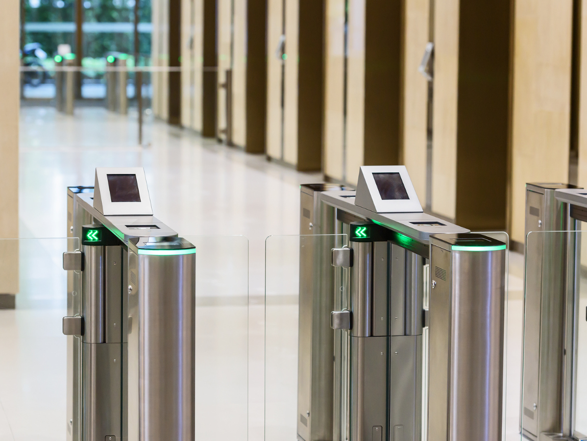 Security turnstiles with illuminated green arrows inside a building.