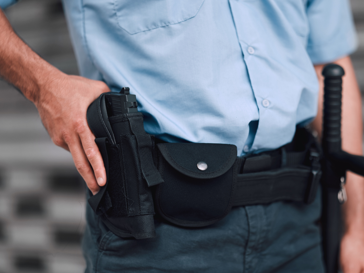 Police officer's uniform, hand near gun holster, baton visible.