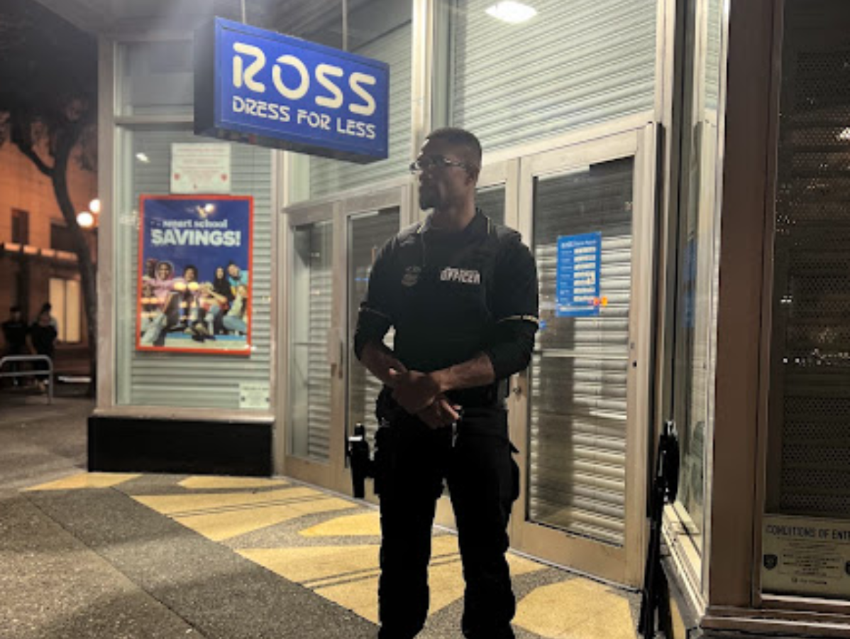 Security guard stands outside a Ross Dress for Less store at night.