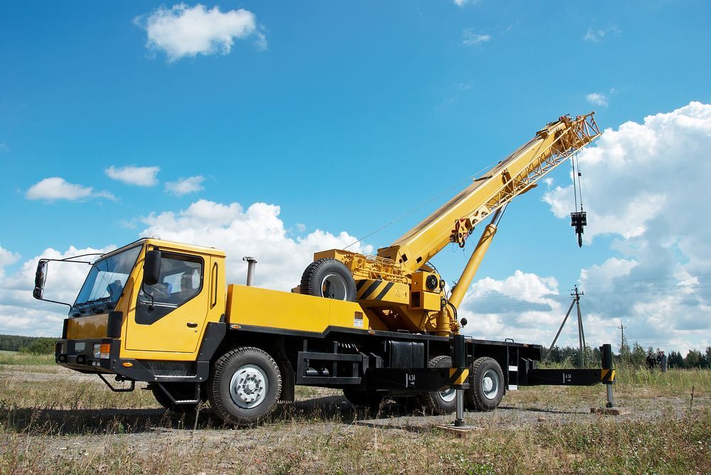 A Yellow Truck With a Crane Attached to It is Parked in a Field — Linmar Cranes & Haulage in Cloncurry, QLD