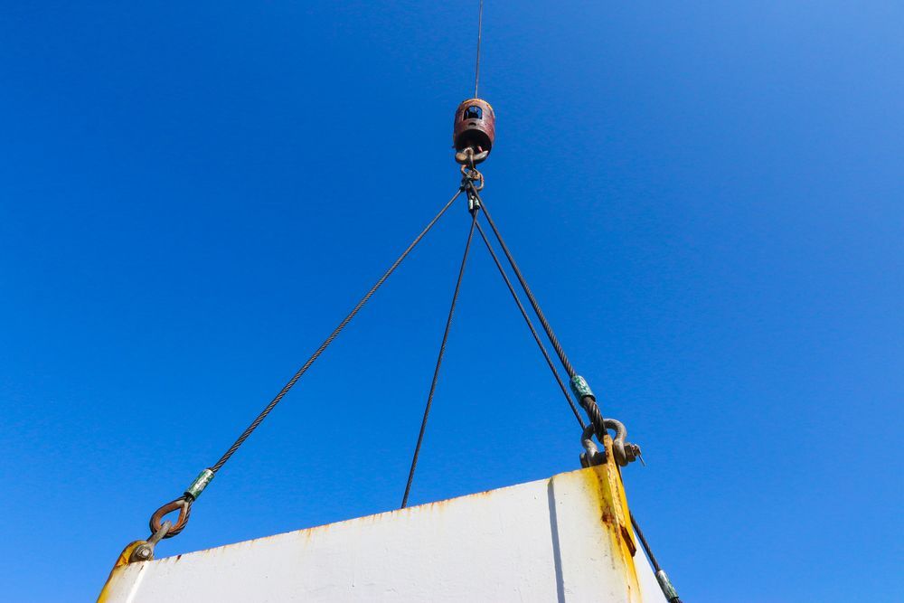 A Crane is Lifting a Container With a Blue Sky in the Background — Linmar Cranes & Haulage in Cloncurry, QLD