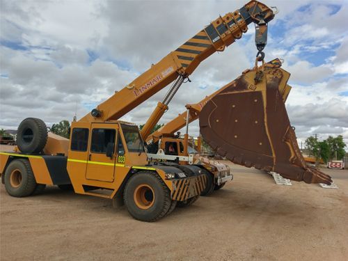 A Yellow Truck With a Crane Attached to It is Carrying a Large Bucket — Linmar Cranes & Haulage in Kalkadoon, QLD