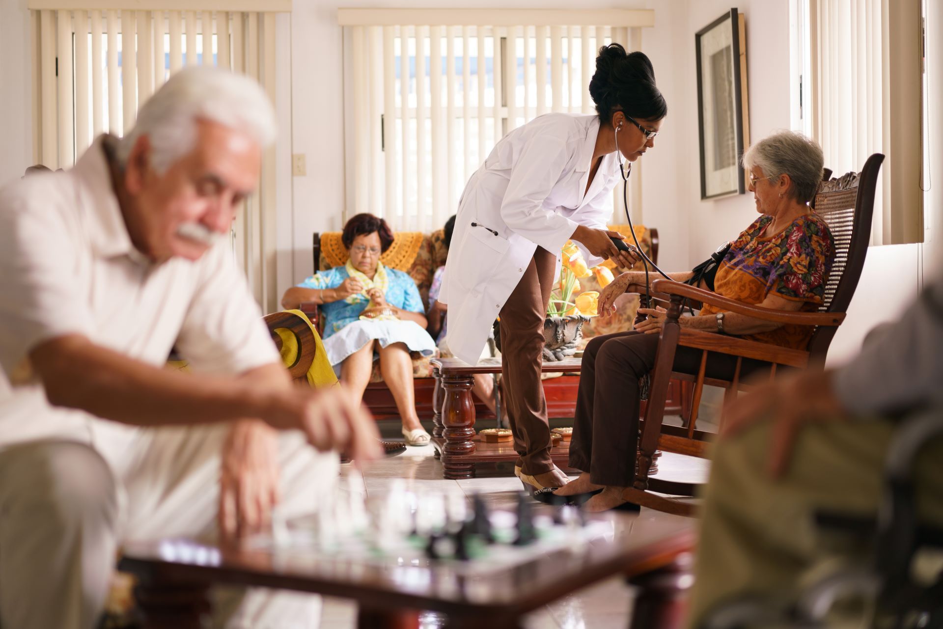 A group of elderly people are playing chess in a living room.