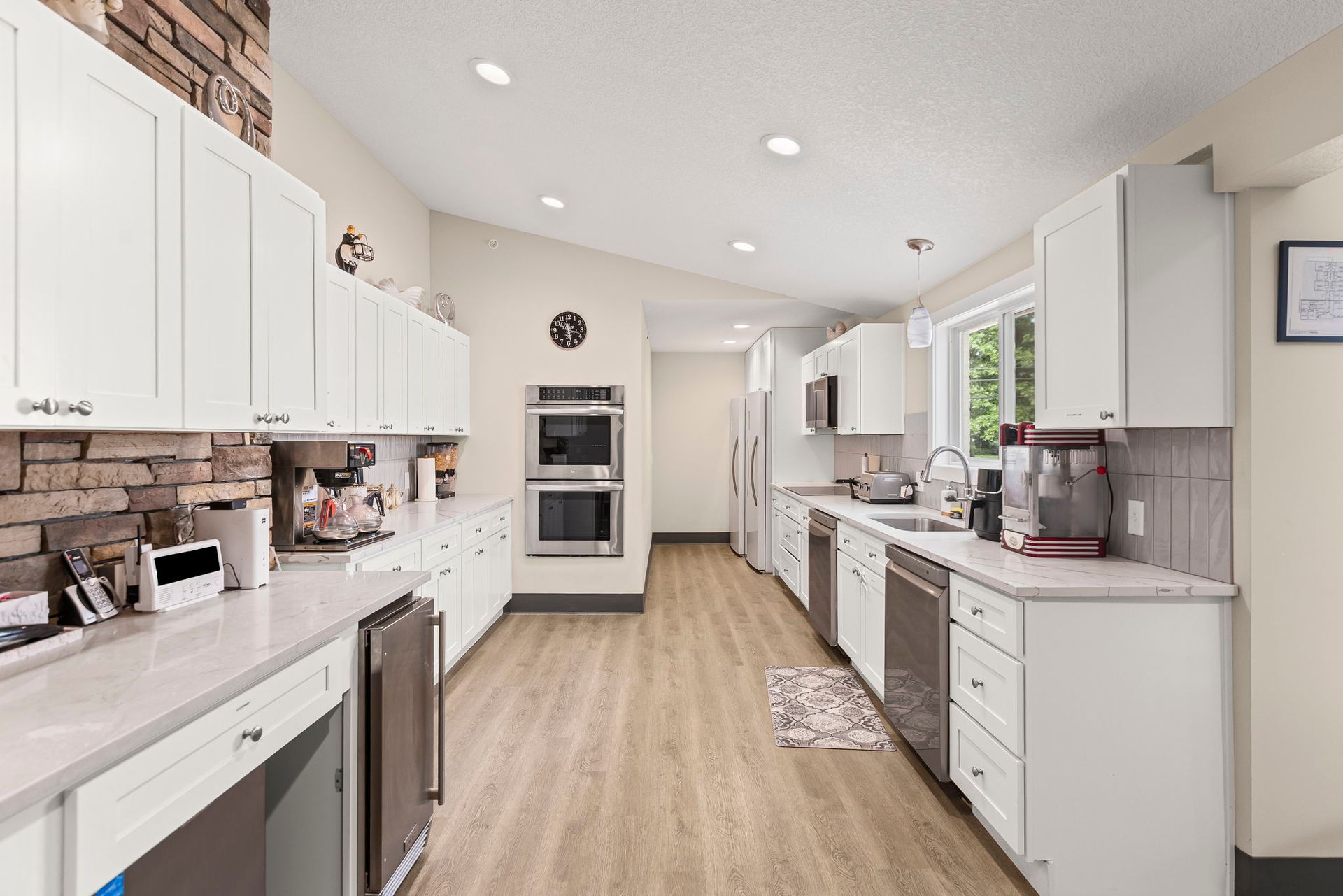 A kitchen with white cabinets , stainless steel appliances , and hardwood floors.