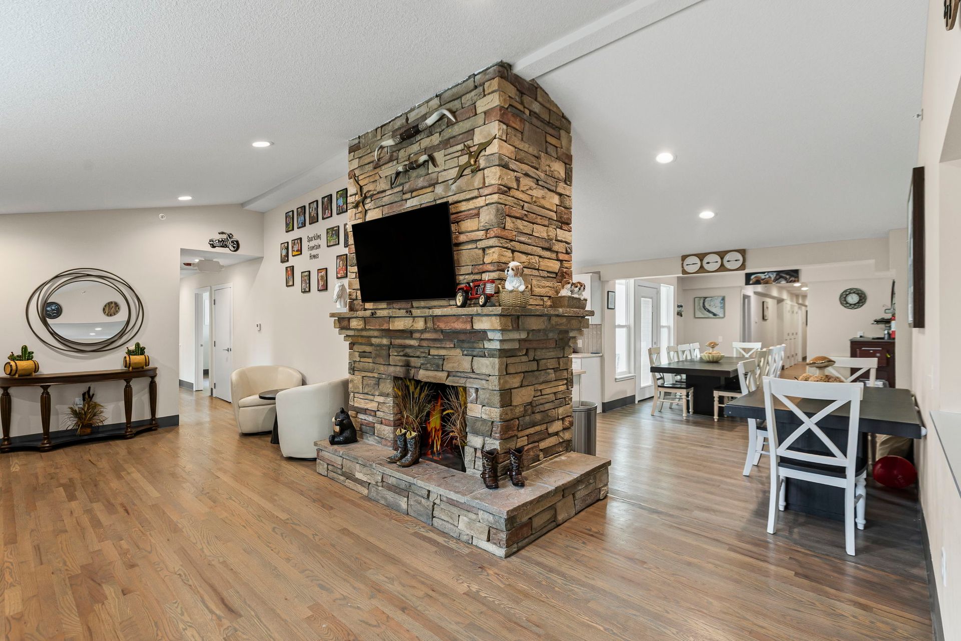 A living room with a stone fireplace and a flat screen tv.