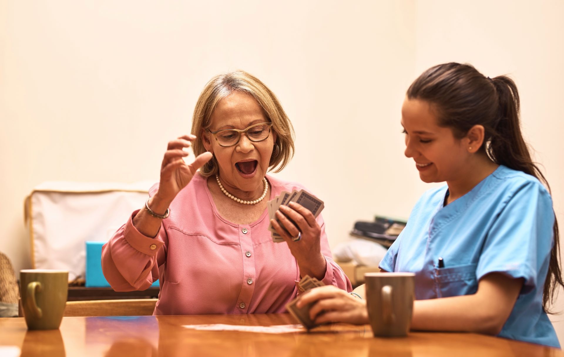 A nurse is helping an elderly woman play a game of cards.
