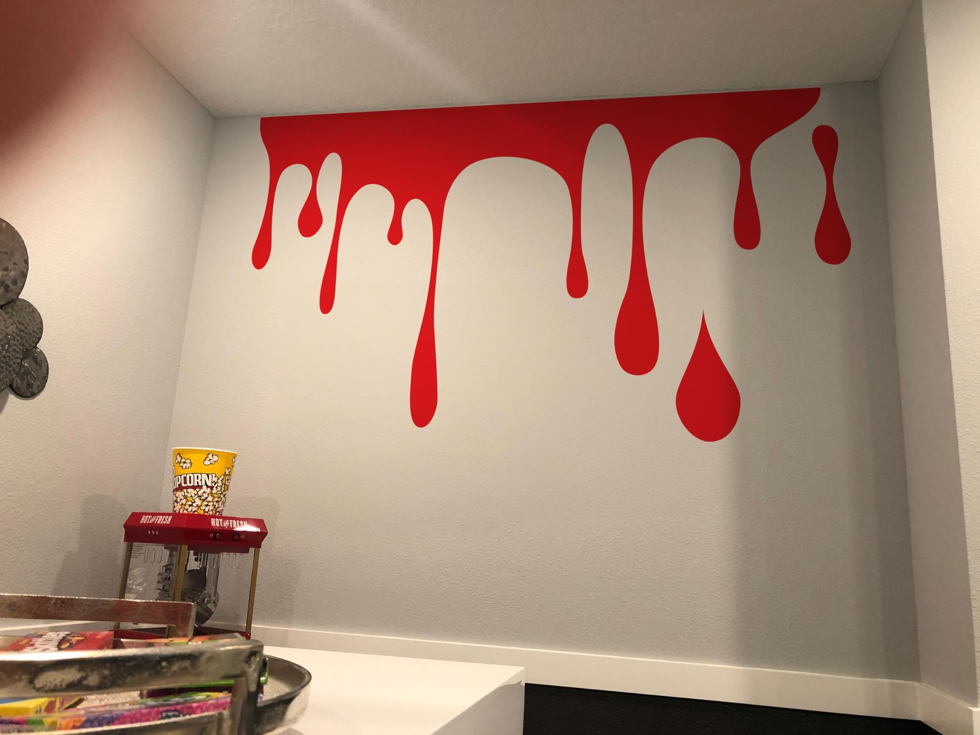 Red paint dripping down a white wall. Paint drips resemble large teardrops.