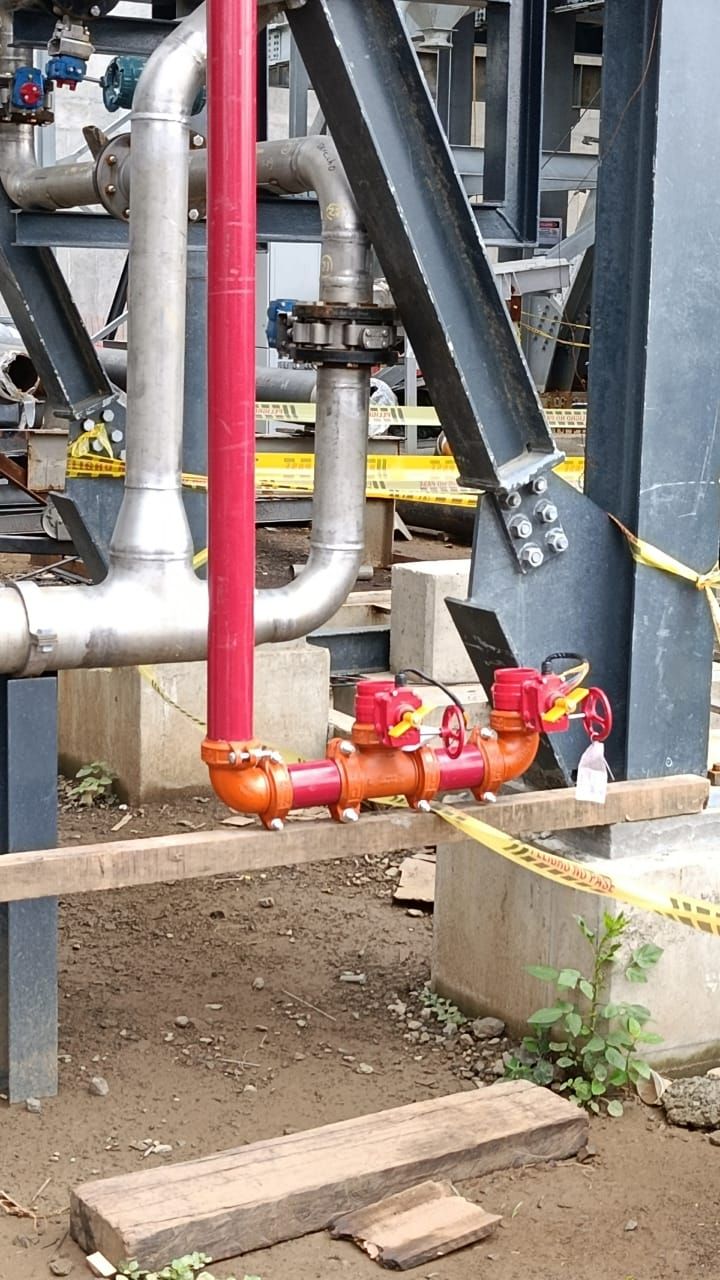 Tuberías y válvulas de extinción de incendios de color rojo en un entorno industrial.