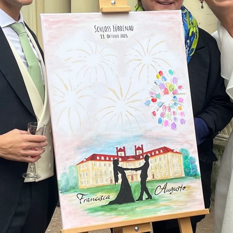 Ein Brautpaar hält ein Bild mit ihren Namen, Datum, Ort und einem Feuerwerk aus Fingerabdrücken hoch