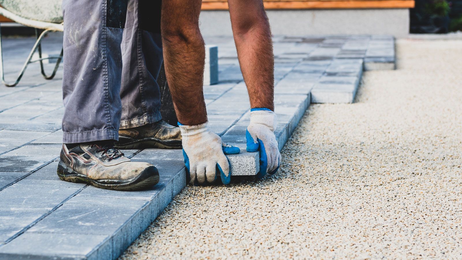 A man is laying bricks on a patio.