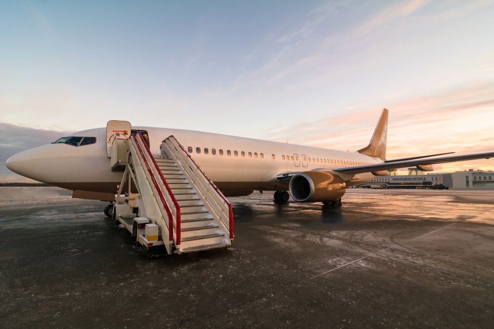 A large passenger jet with stairs attached to it is parked on the tarmac at an airport.