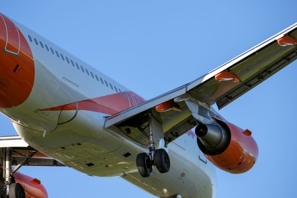 An orange and white airplane is flying in the sky