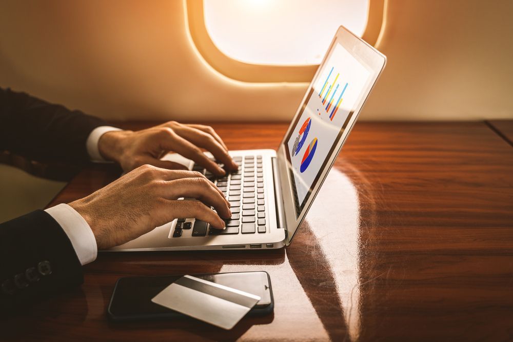 A man is typing on a laptop on an airplane.