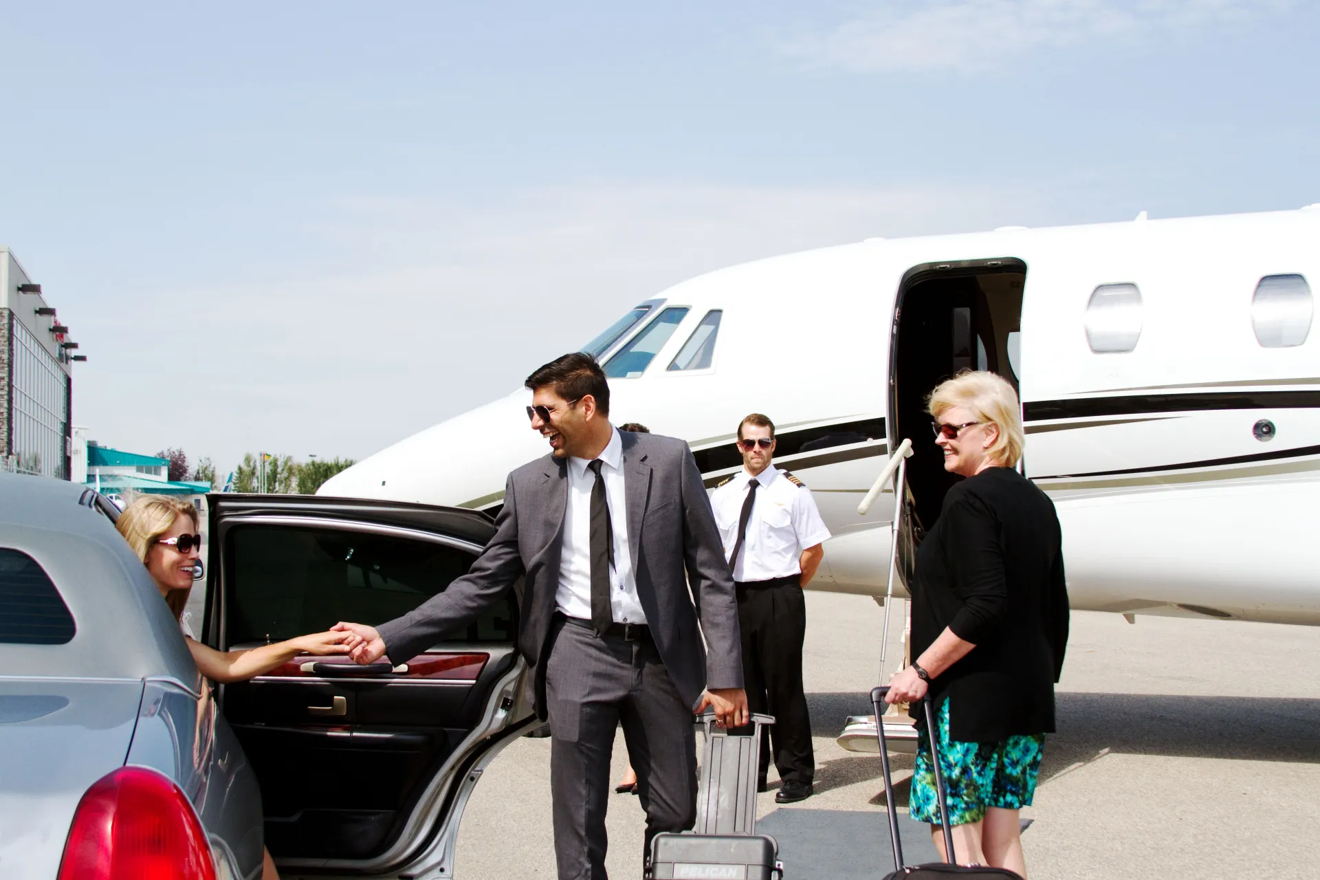 A man in a suit is shaking hands with a woman in front of a plane