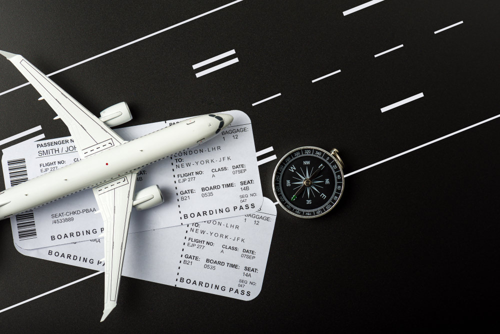 An airplane is sitting on top of a boarding pass and a compass