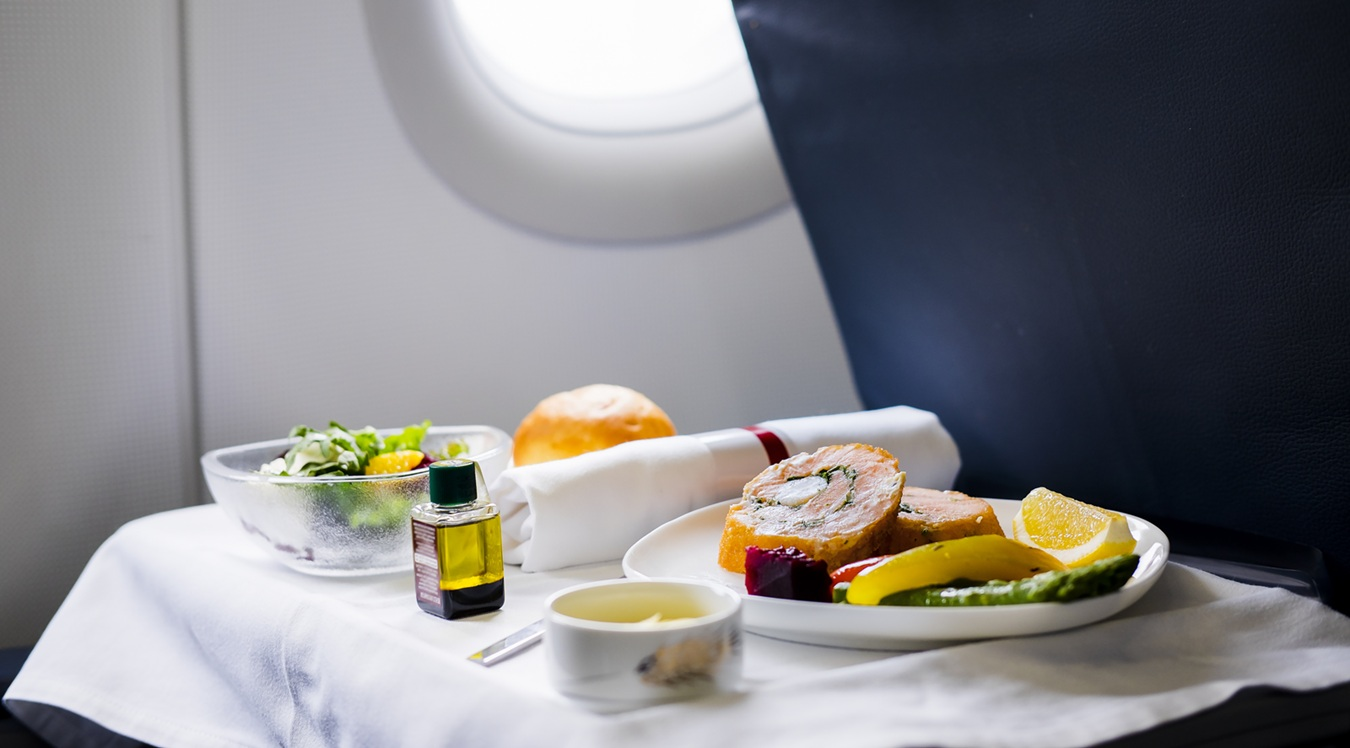 A luxury private jet meal with a menu card displaying premium winter dishes and prices