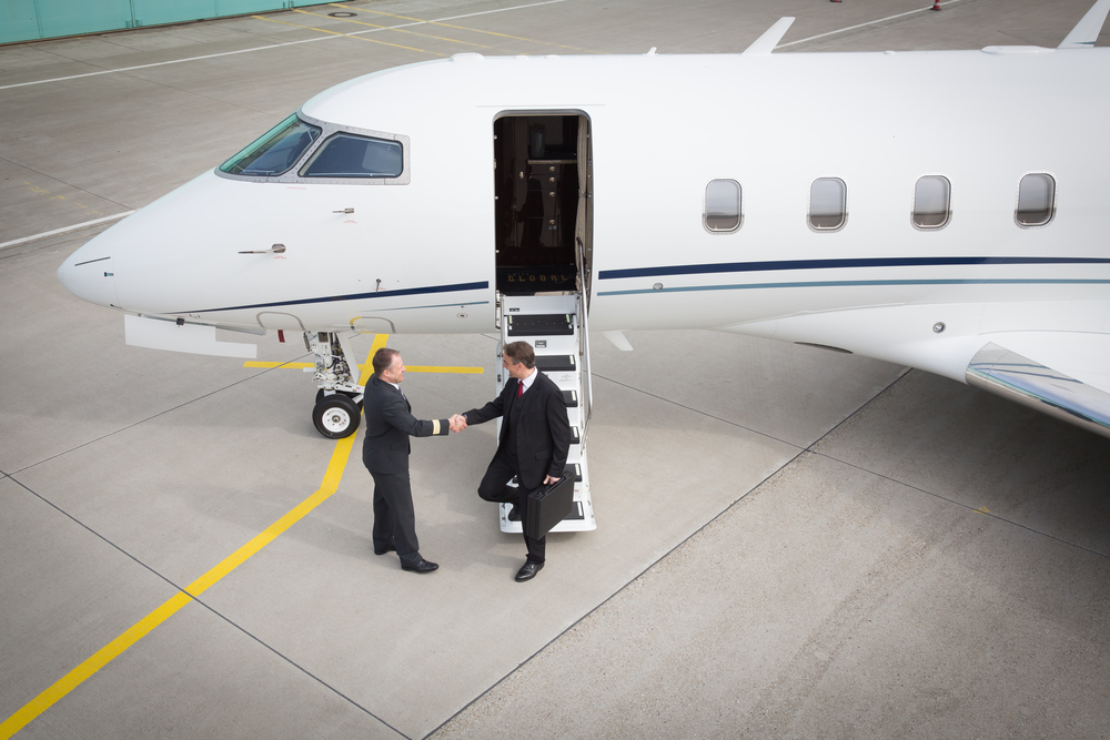 Two men shaking hands in front of a private jet