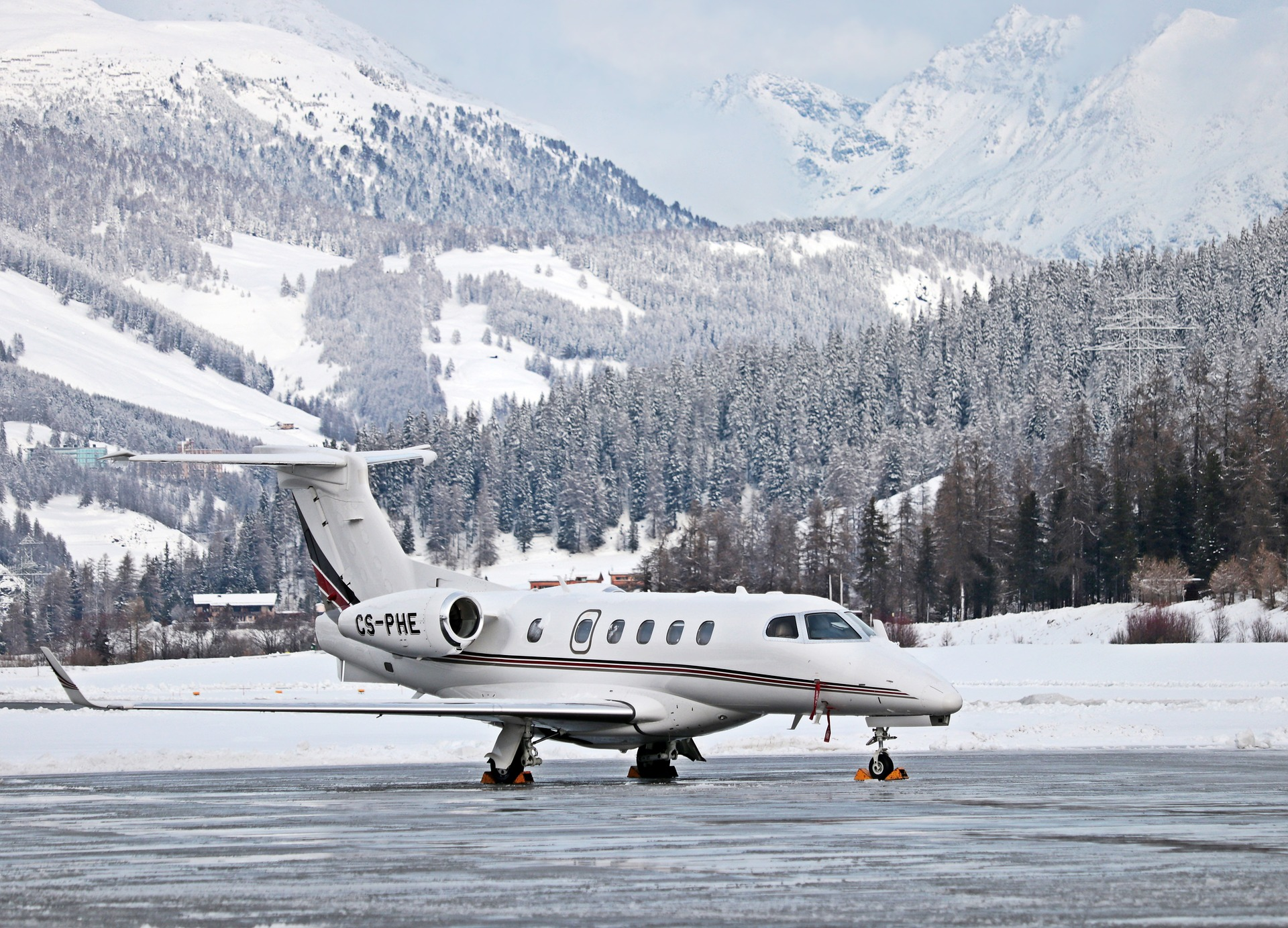 A luxury private jet parked on a snowy runway with scenic Australian mountains in the background