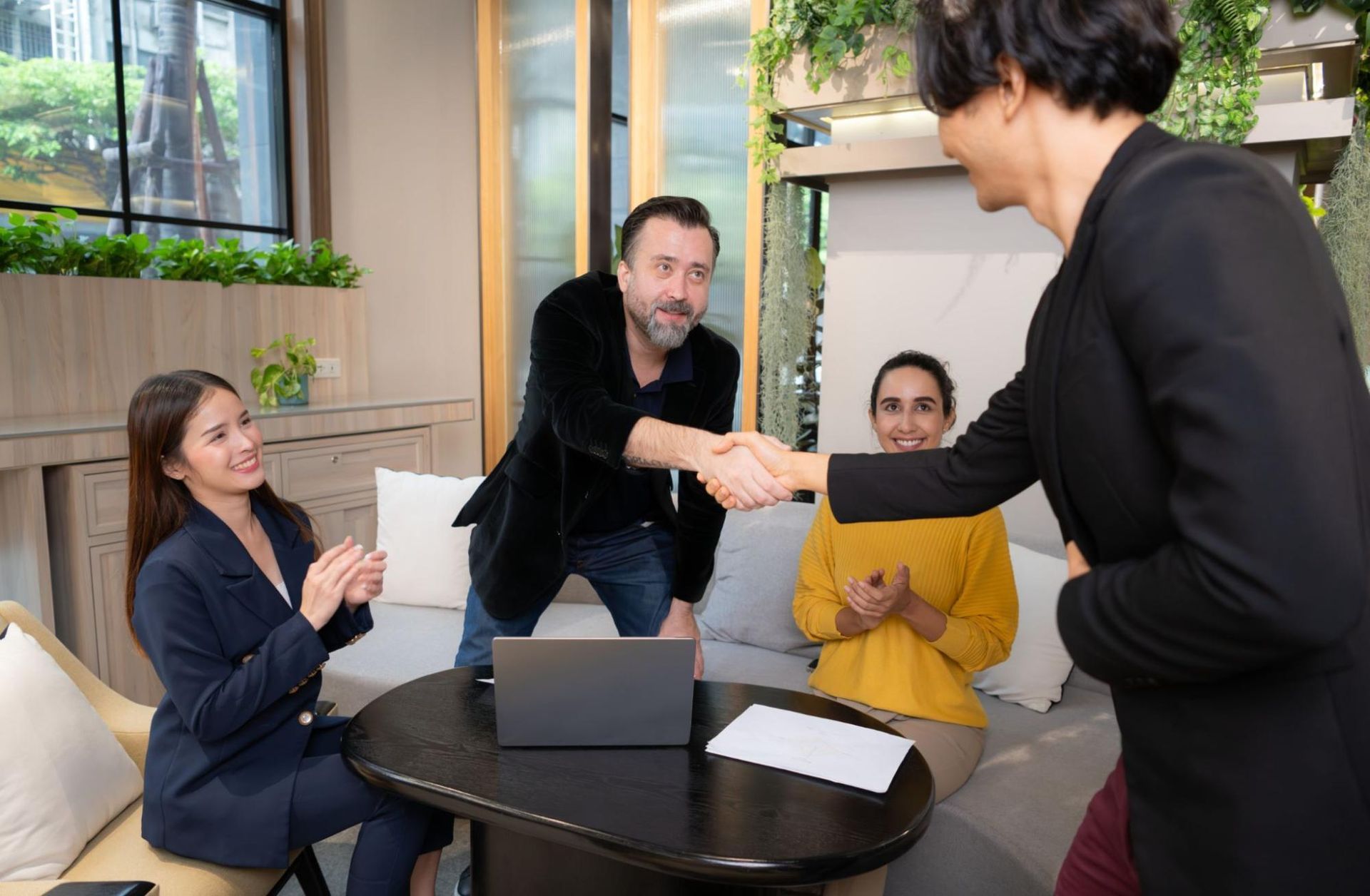 A group of people are sitting around a table shaking hands.
