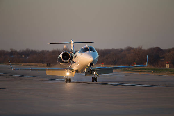 A private jet taxiing on the runway at a major Australian airport, with terminal buildings in the background