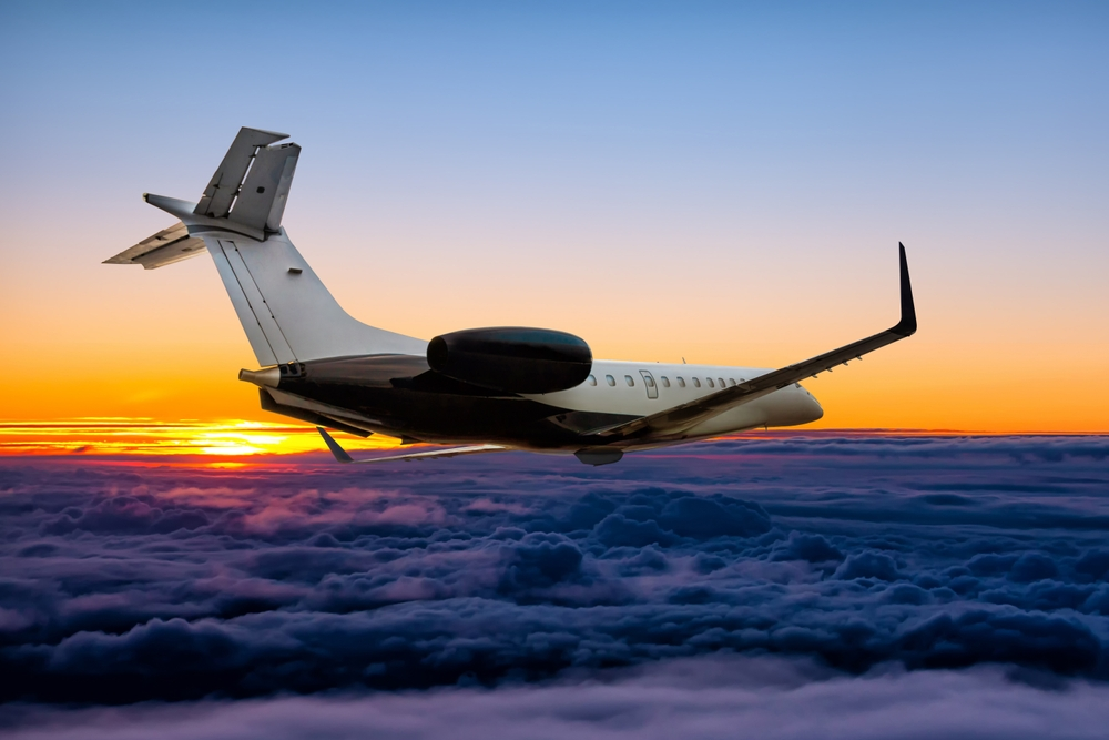 A private jet is flying through the clouds at sunset.