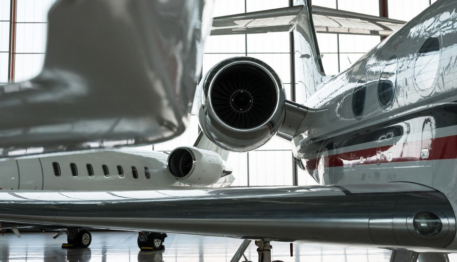 Passengers relaxing in a private jet FBO lounge before boarding, with staff assisting