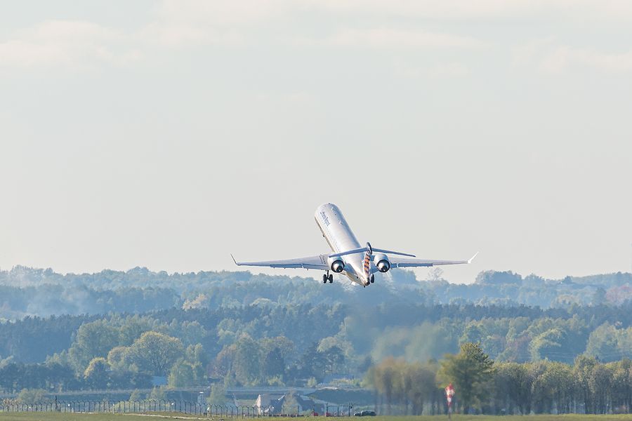 a large jetliner flying over a lush green field