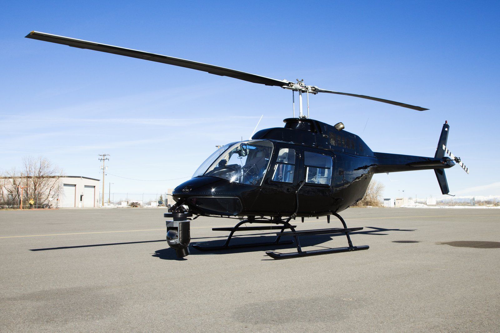 a black helicopter sitting on top of an airport tarmac