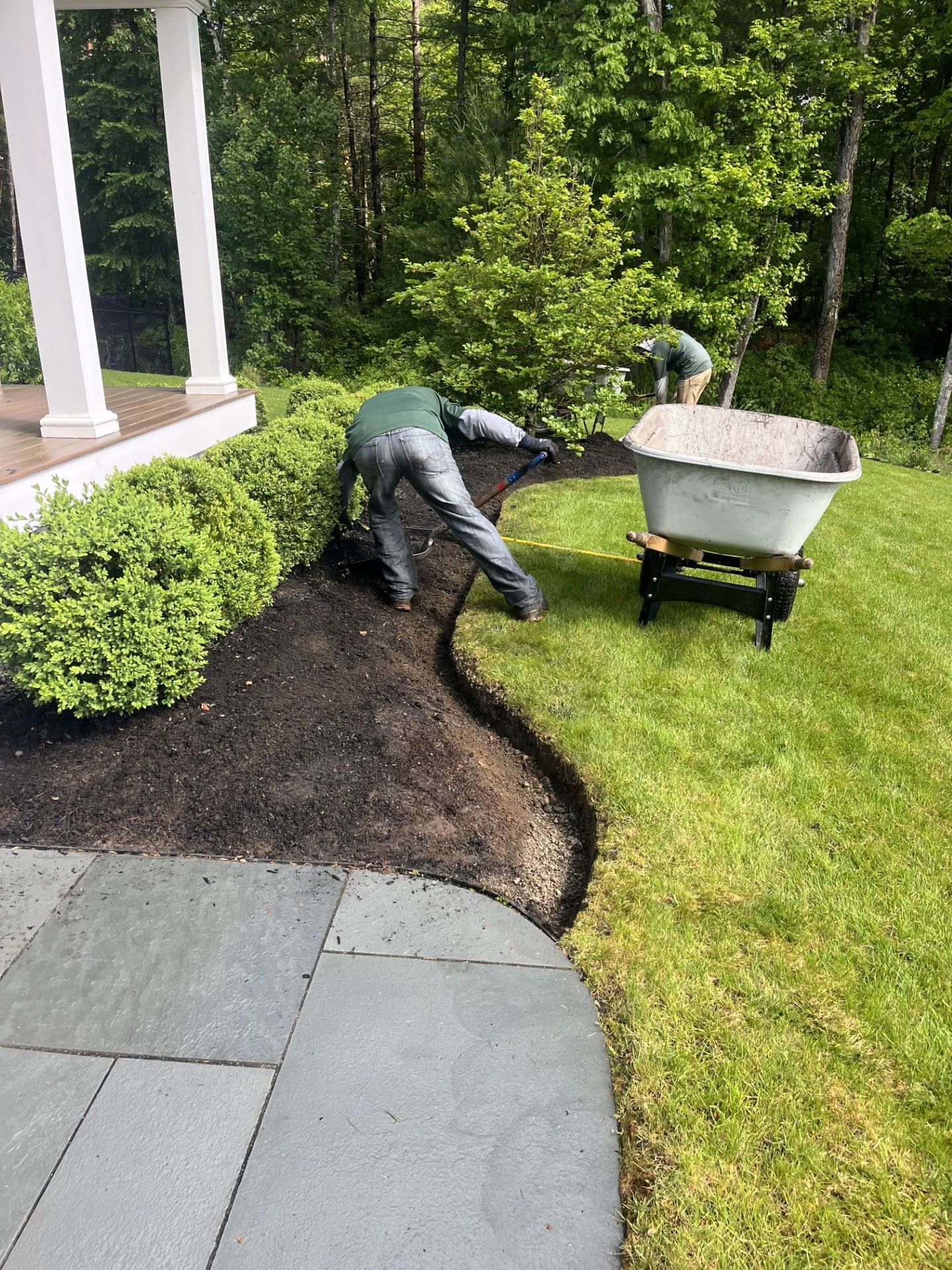A semicircular stone retaining wall holding a garden bed in front of a house with beige siding and a purple front door.