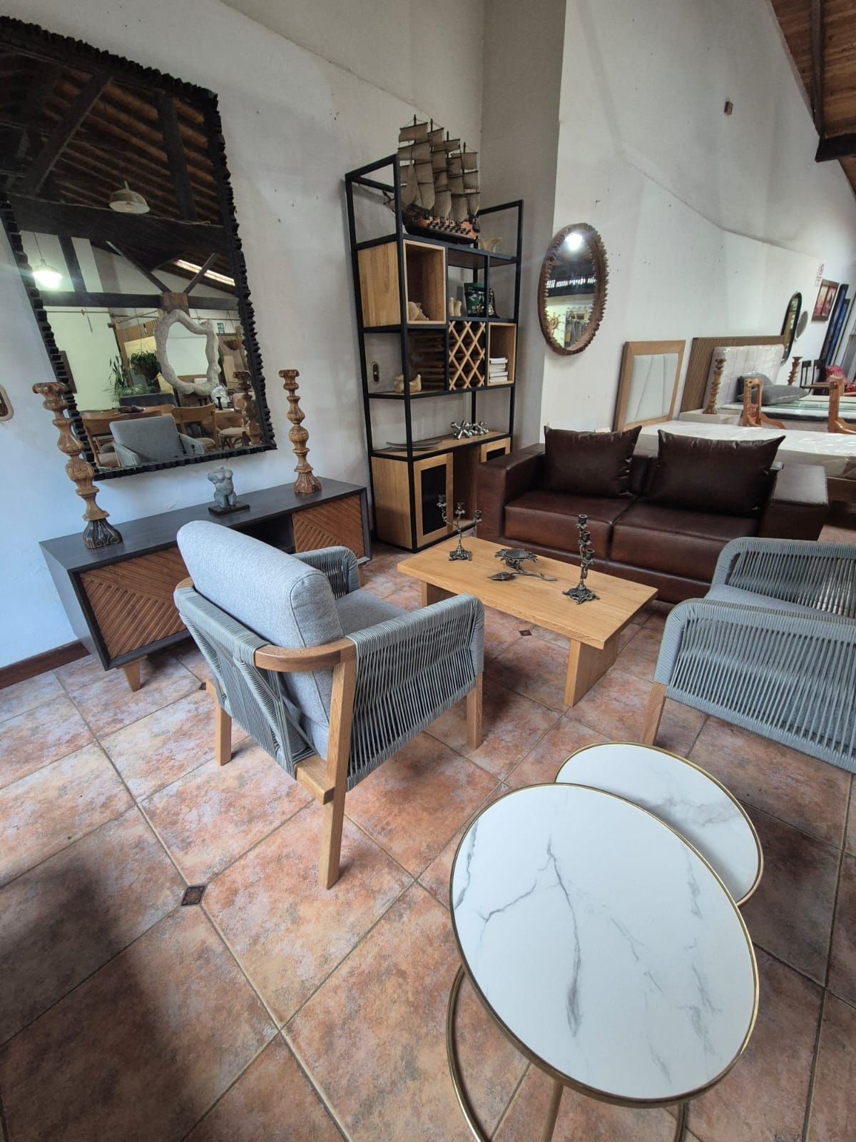 Salón con muebles de madera, incluyendo sofá, sillas y estanterías, en un ambiente rústico.