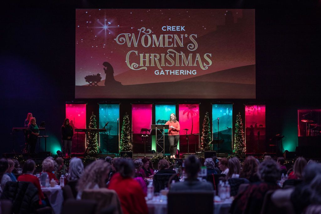 A group of people are sitting in front of a screen that says women 's christmas gathering