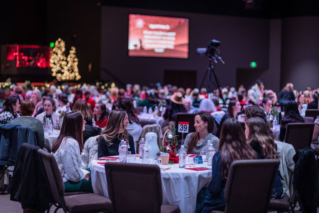 A large group of people are sitting at tables at a christmas party.