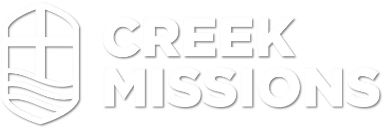 A white logo for creek missions with a cross and shield.