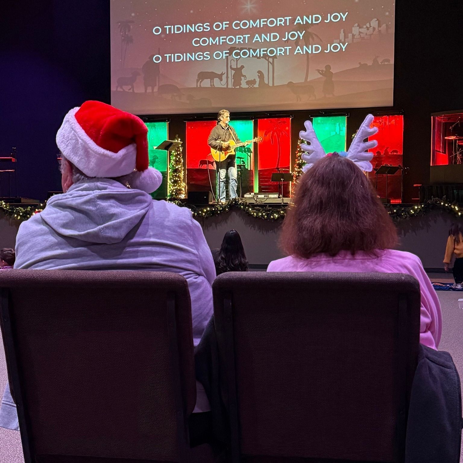 A man and a woman are sitting in chairs watching a christmas concert.