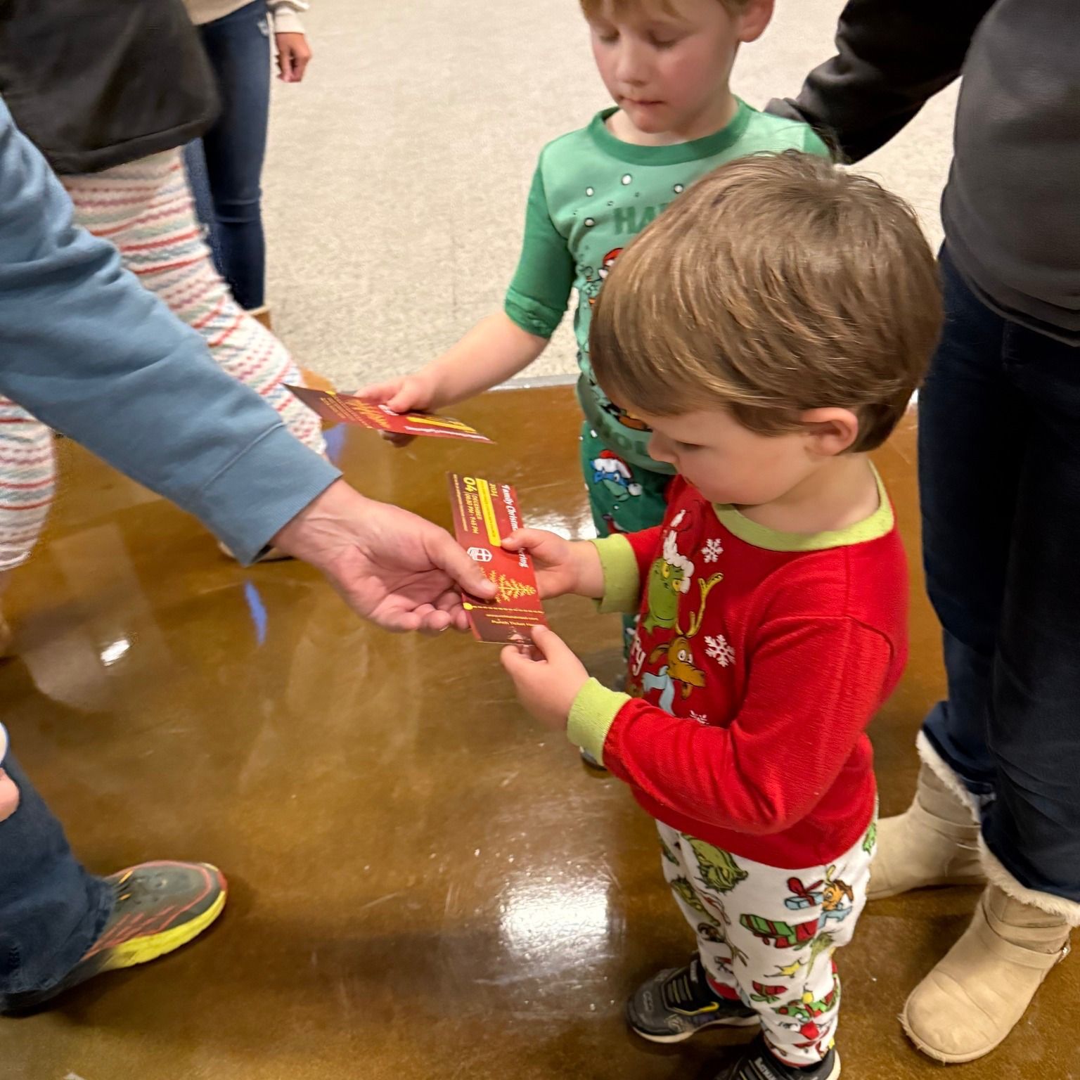 A little boy in a red shirt is holding a piece of paper